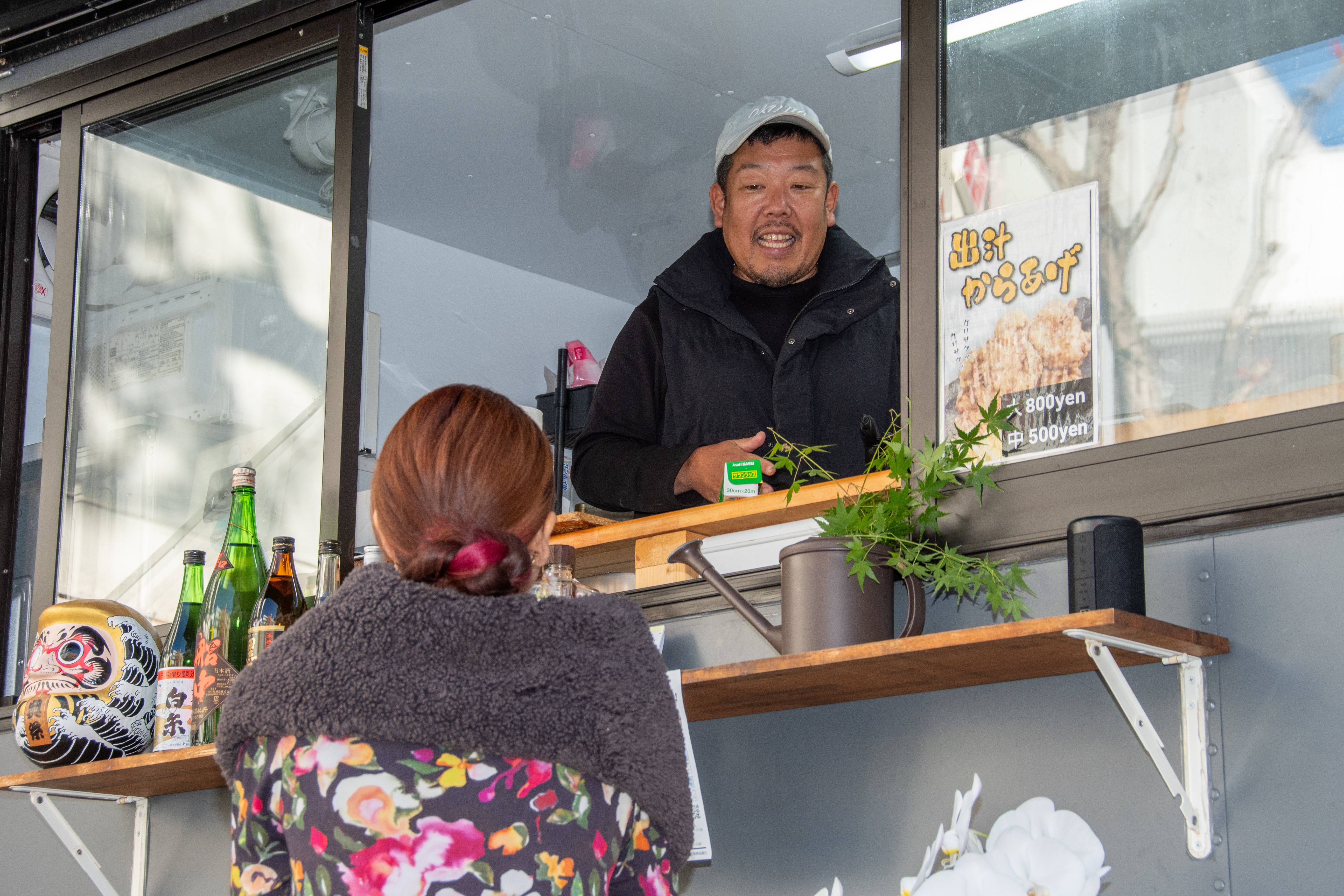 カウンター越しに常連客と会話する白和忠高