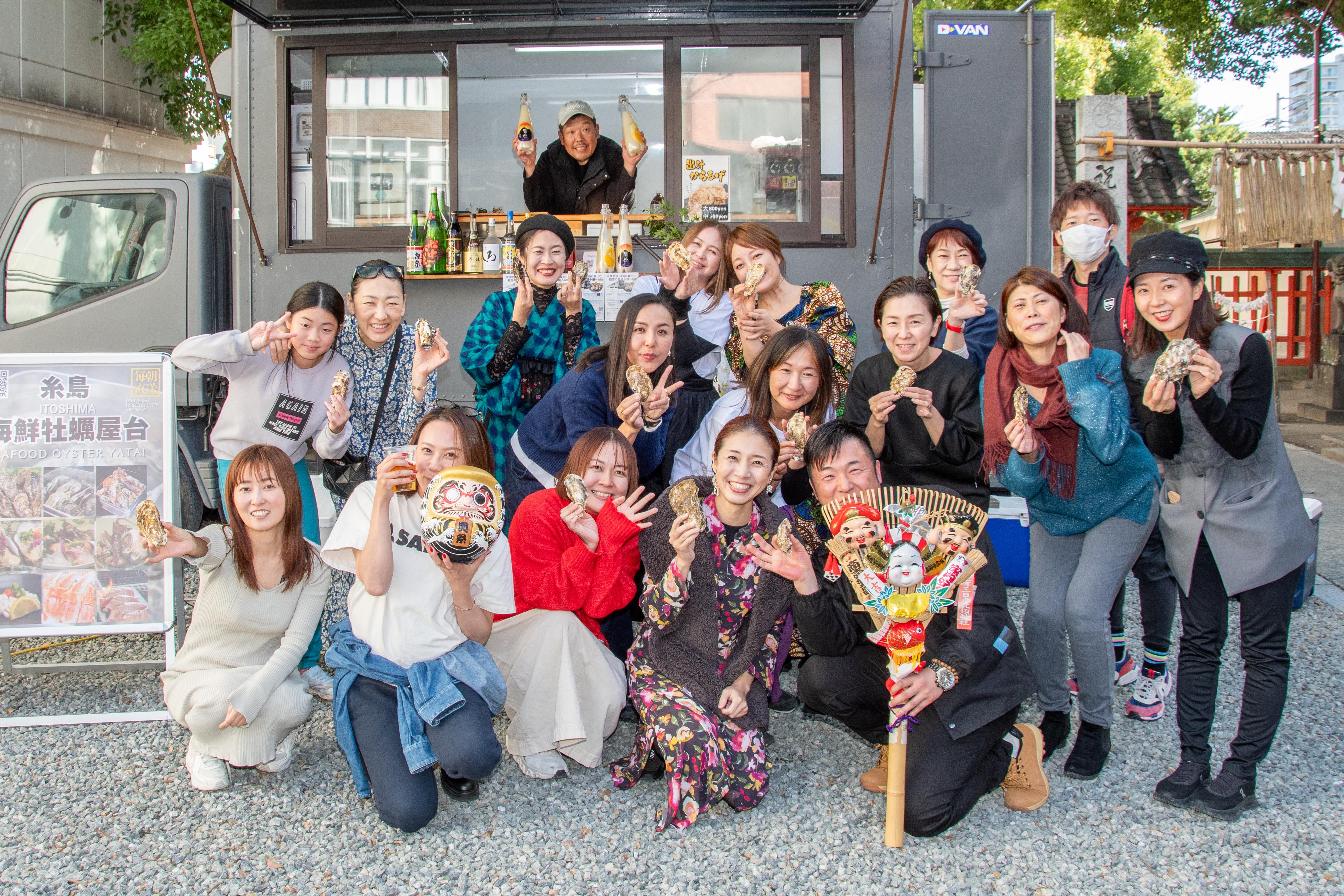 奥糸の前で牡蠣を手に笑顔で集まるお客様と白和忠高